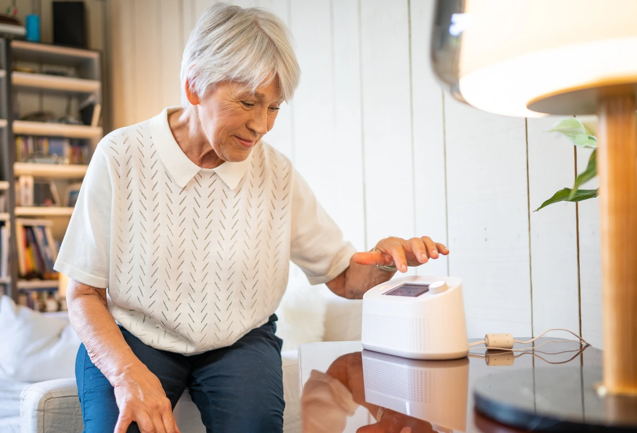 Vibby Homecare Fall Detector for Independent Living Older woman using a Vibby Homecare fall detector device on a table at home