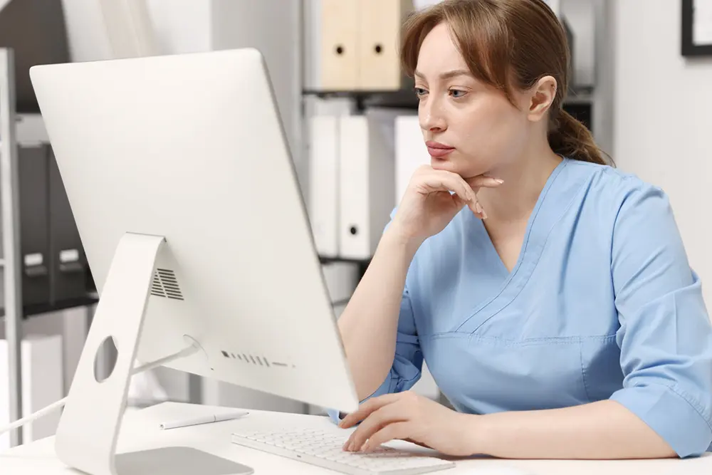 Healthcare administrator reviewing nurse call alarm reports on a desktop computer