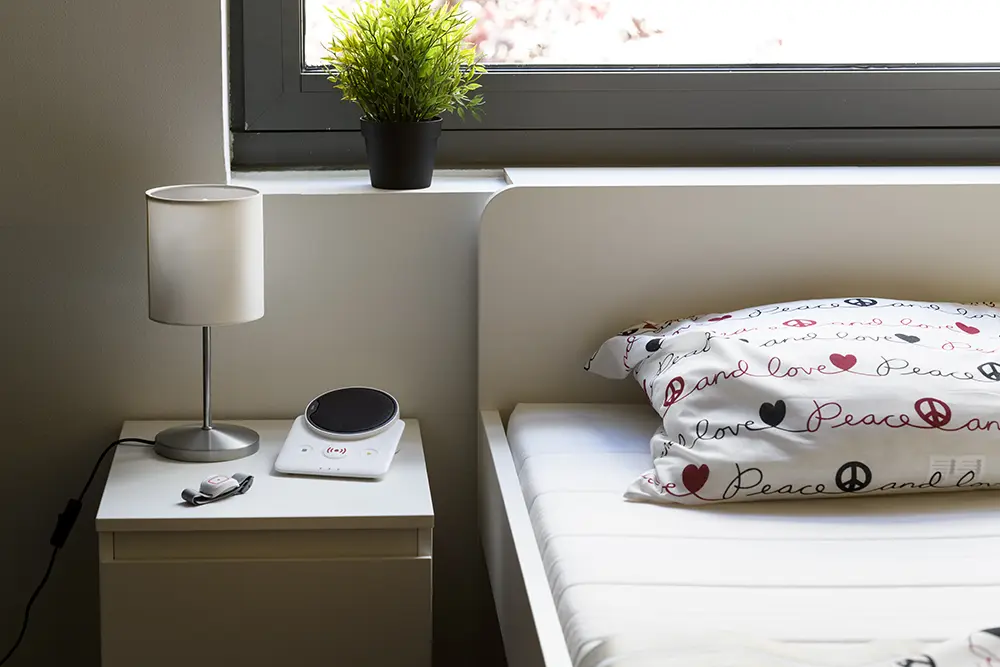 Possum Novo digital carephone connected with telecare peripherals beside a bed in a home environment