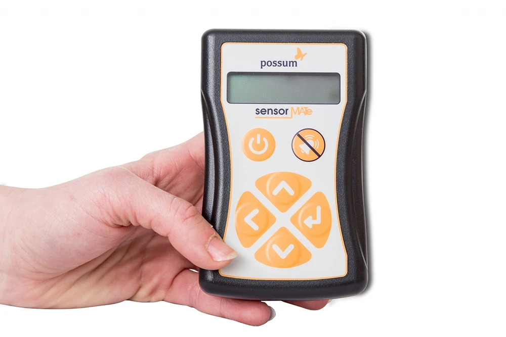 Hand holding the Sensor MATe monitoring device with simple keypad and display for quick setup and programming
