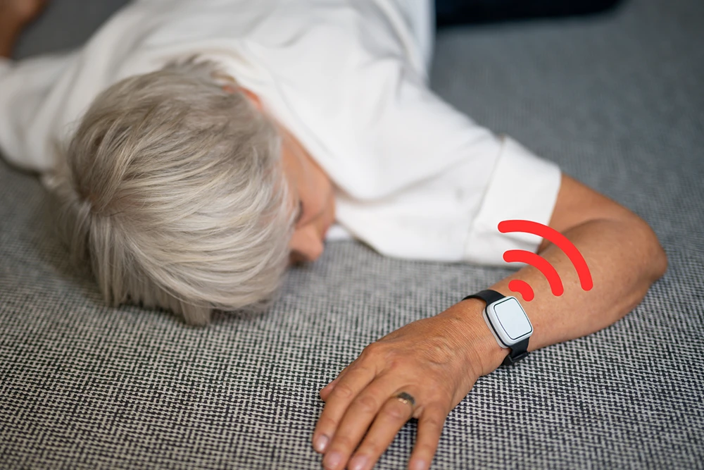 person wearing a Vibby Oak fall detection device after a fall, with automatic emergency alert activated
