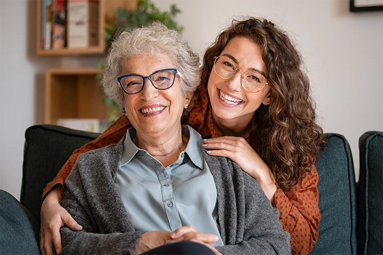 Reassurance and Support with Personal Alarms elderly woman sitting with carer smiling at home representing reassurance independence and personal alarm support