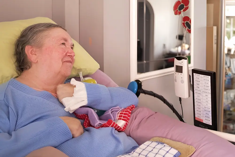 Floor Mounted Controller for Bedside Use woman in bed using assistive communication device mounted on floor stand