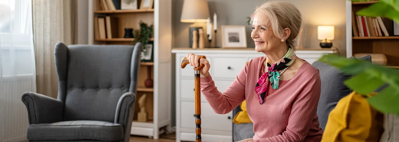elderly woman at home with walking stick representing independent living and home safety support