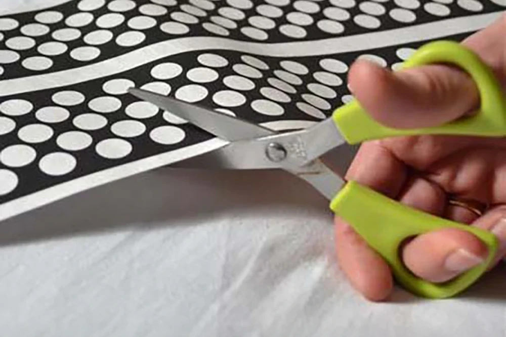 Bed Sense ultra-slim bed occupancy sensor being cut to size for discreet installation under bedding or upholstery