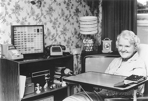 Historic photograph of a woman using the Possum PSU 3 environmental control system in her home in 1975