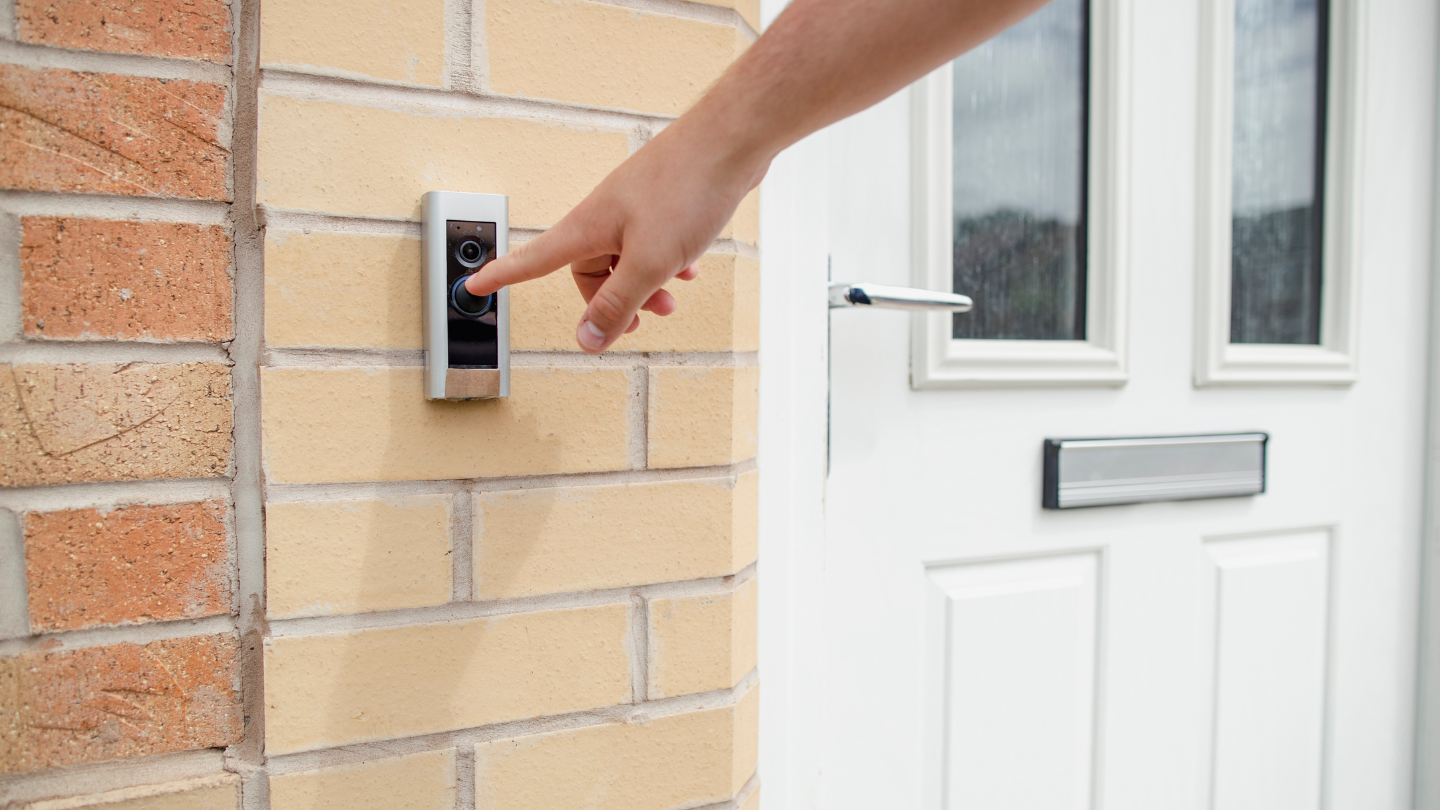 Home Control – Telephones & Intercoms hand pressing doorbell outside house
