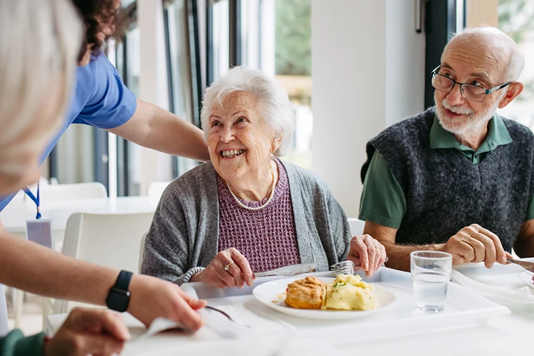 Keeping Residents Safe Around the Clock Care home staff supporting residents during mealtime in a communal dining area