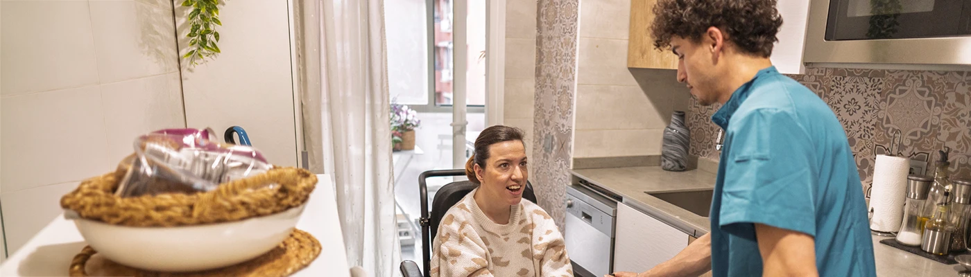 Care worker supporting an elderly resident in a care home, illustrating assisted living technology and person-centred care.