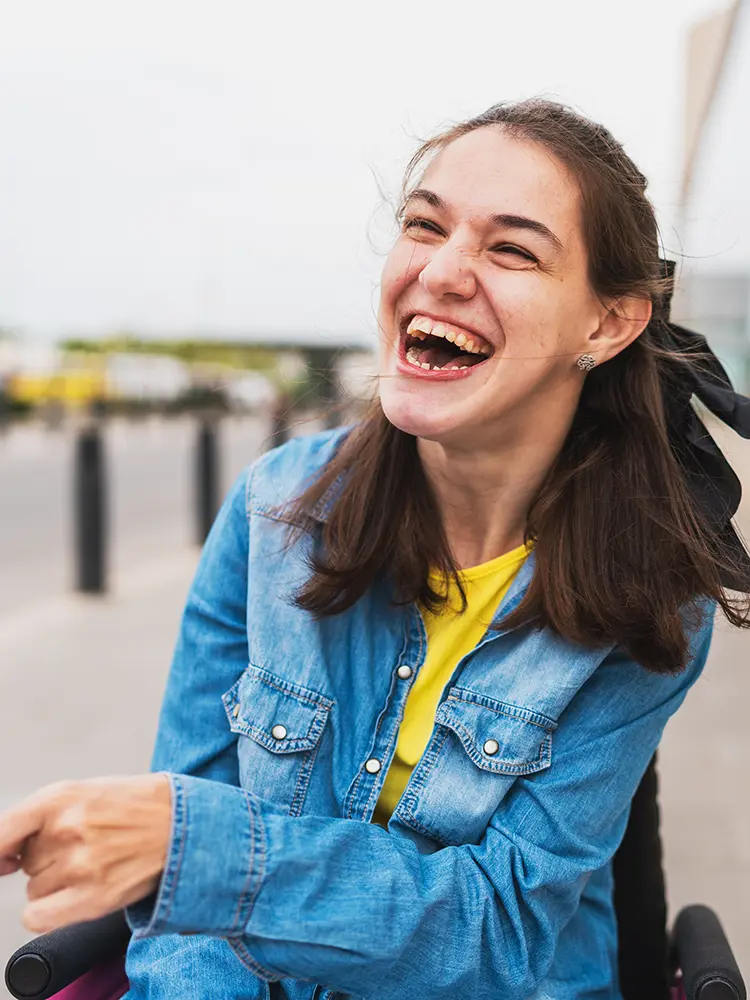 Young wheelchair user smiling outdoors, representing greater independence through environmental control systems