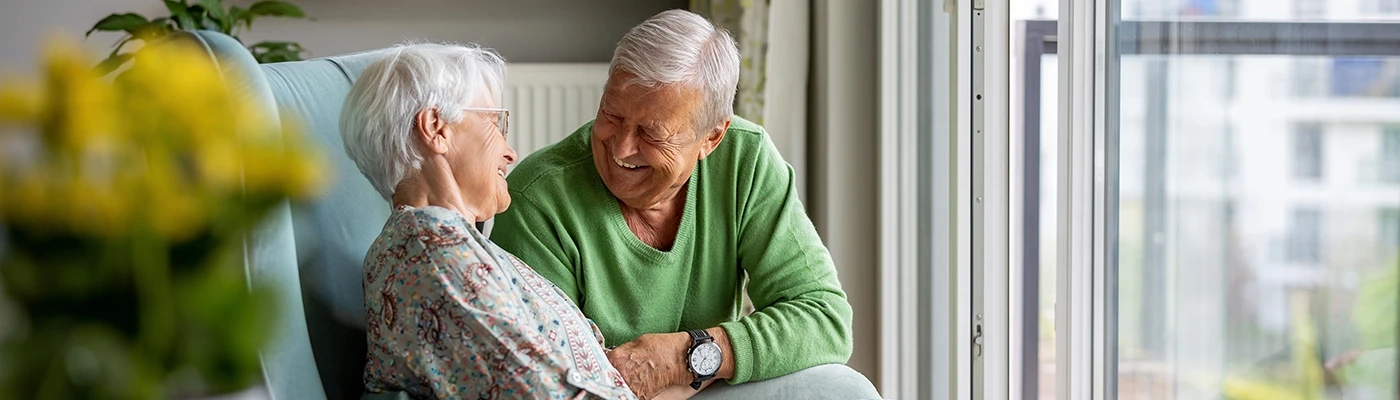 Happy Elderly Couple at Home – Independent Living and Wellbeing Smiling elderly couple sitting together at home promoting independent living and wellbeing