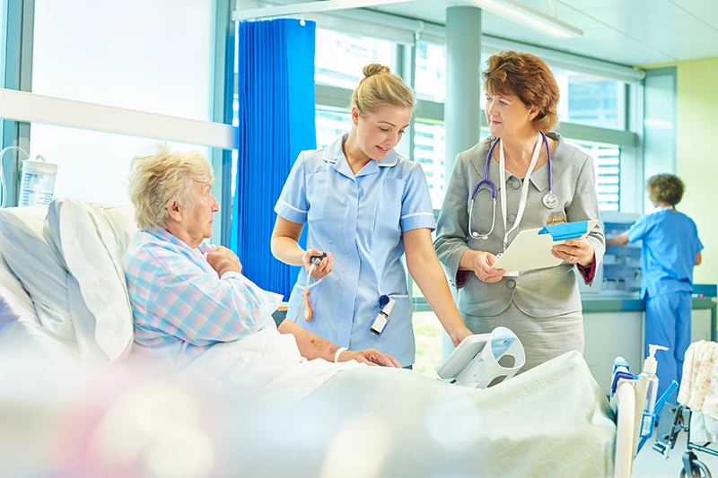 Healthcare professionals supporting an older patient in a hospital ward