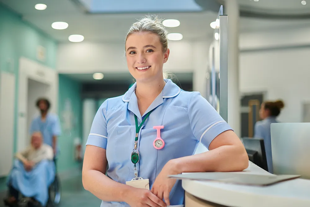 Care home nurse at a reception desk representing location-based emergency response, enabling colleagues to quickly identify and reach staff in need of assistance.