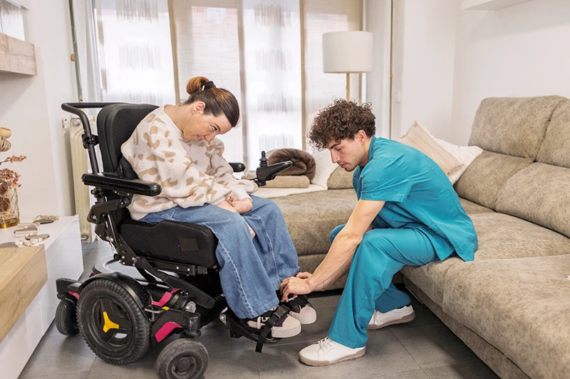 Care worker assisting a wheelchair user in a supported living home environment