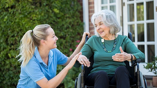 Supporting Safer Care Through Technology Care worker supporting an older wheelchair user outdoors to promote safe, independent living